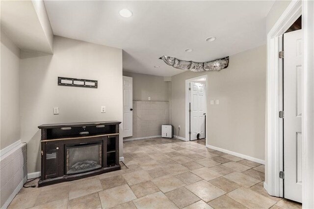 unfurnished living room featuring recessed lighting, baseboards, and a glass covered fireplace