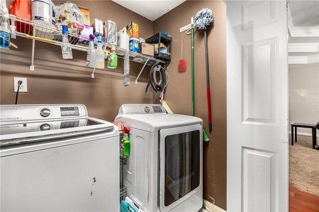 clothes washing area featuring laundry area, washing machine and dryer, and wood finished floors