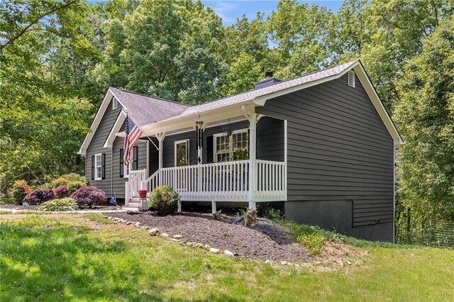 single story home with roof with shingles, a chimney, a porch, and a front yard