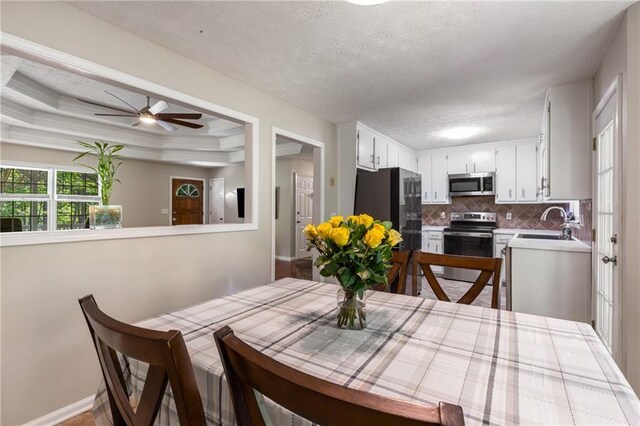 dining area featuring baseboards, ceiling fan, and a textured ceiling
