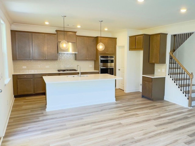 62 Sheryl Way, Loganville, GA 30052 - kitchen with stainless steel appliances, wall chimney range hood, a sink, light wood finished floors, and crown molding