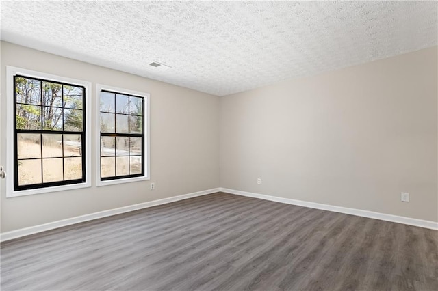 801 Hemingway Rd, Stone Mountain, GA 30088 - unfurnished room with visible vents, dark wood finished floors, a textured ceiling, and baseboards