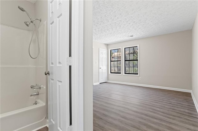 801 Hemingway Rd, Stone Mountain, GA 30088 - full bath with bathtub / shower combination, baseboards, a textured ceiling, and wood finished floors
