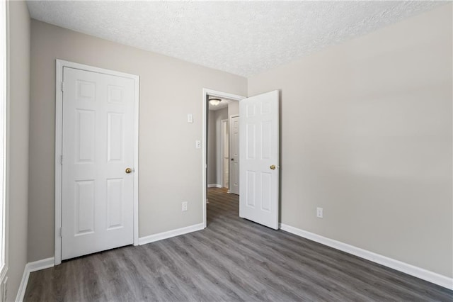 801 Hemingway Rd, Stone Mountain, GA 30088 - unfurnished bedroom with a textured ceiling, baseboards, and dark wood-style flooring