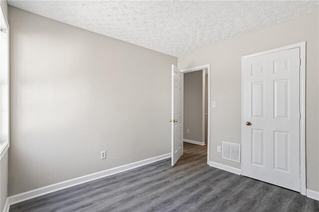 801 Hemingway Rd, Stone Mountain, GA 30088 - unfurnished bedroom featuring dark wood-style floors, visible vents, a textured ceiling, and baseboards