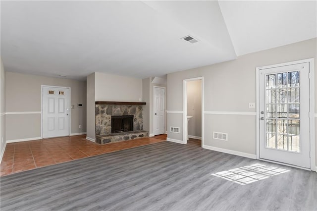 801 Hemingway Rd, Stone Mountain, GA 30088 - unfurnished living room with a stone fireplace, wood finished floors, visible vents, and baseboards