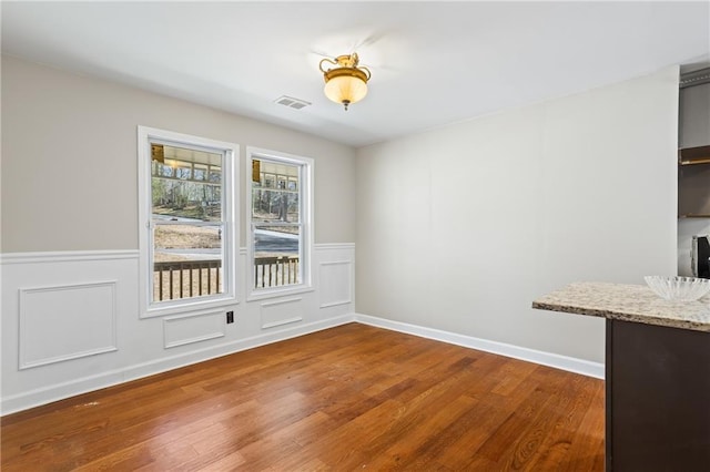 801 Hemingway Rd, Stone Mountain, GA 30088 - unfurnished dining area with wainscoting, wood finished floors, visible vents, and a decorative wall