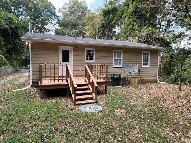 back of property with a lawn and a deck