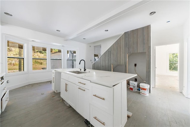 kitchen featuring light stone counters, white cabinetry, a kitchen island with sink, light hardwood / wood-style flooring, and sink