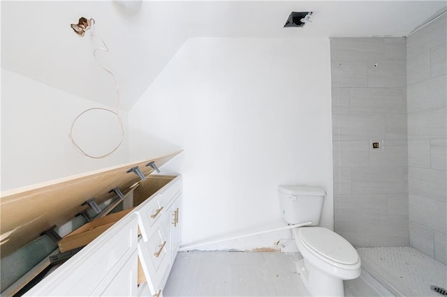 bathroom with vanity, toilet, and tiled shower