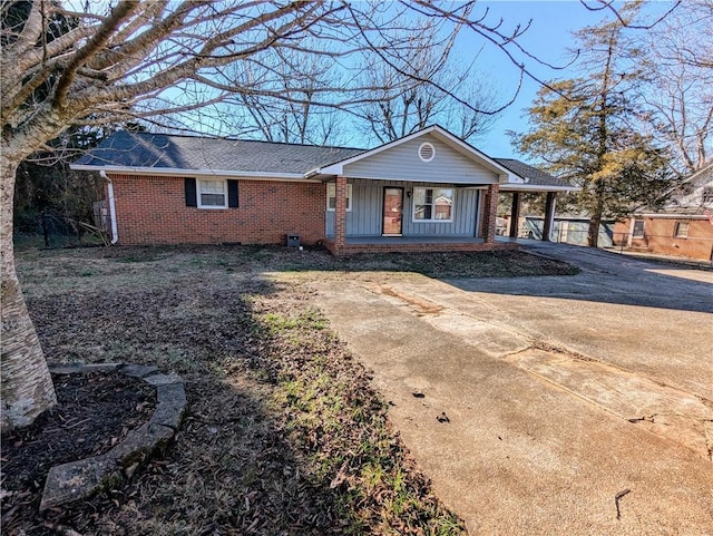 single story home featuring a porch, concrete driveway, brick siding, and roof with shingles