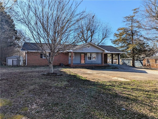 view of front of house with driveway, an attached carport, fence, an outdoor structure, and brick siding