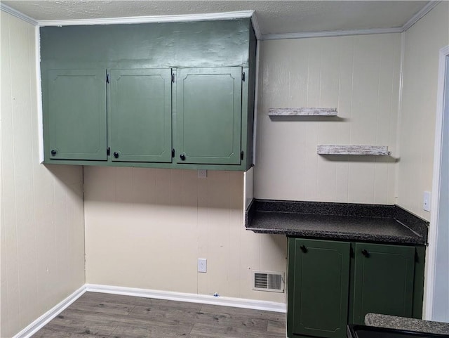 interior space with wood finished floors, visible vents, baseboards, green cabinets, and dark countertops