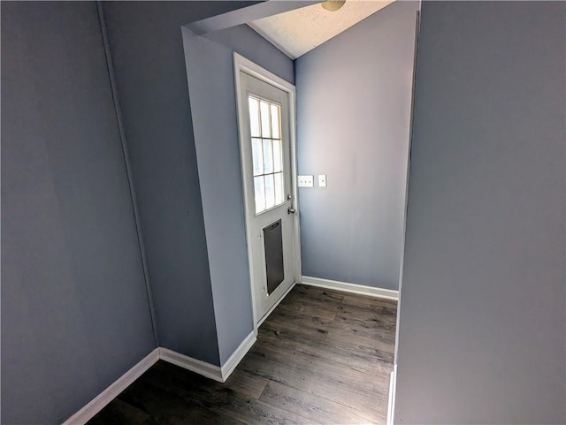 doorway featuring a textured ceiling, dark wood finished floors, and baseboards