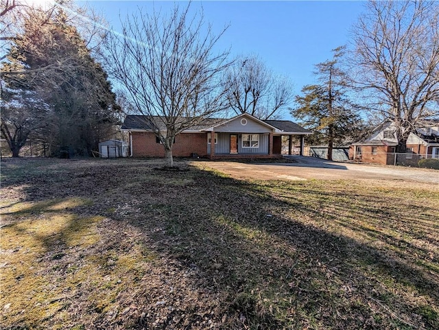 single story home with a porch, brick siding, an outdoor structure, fence, and a shed