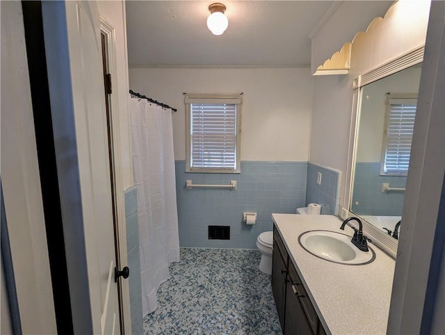 full bathroom with toilet, a wainscoted wall, tile patterned floors, vanity, and tile walls