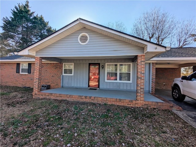 view of front of house featuring covered porch, a carport, and brick siding