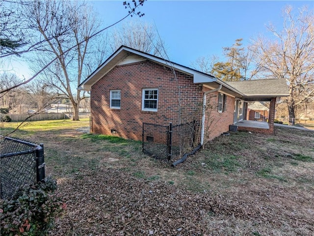 view of side of home featuring crawl space, brick siding, and fence