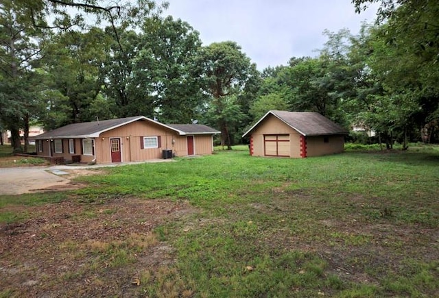 view of front of house featuring cooling unit, an outbuilding, a garage, and a front yard