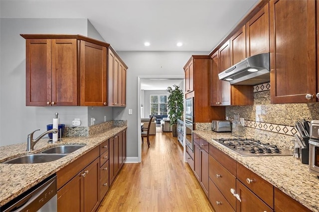 kitchen with light stone countertops, decorative backsplash, stainless steel appliances, sink, and light hardwood / wood-style floors