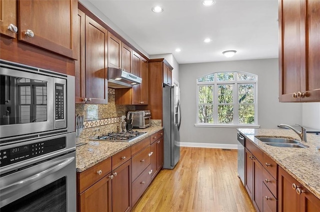 kitchen featuring tasteful backsplash, light stone counters, sink, and appliances with stainless steel finishes