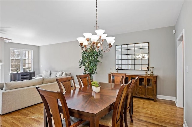 dining space featuring ceiling fan with notable chandelier and light hardwood / wood-style flooring