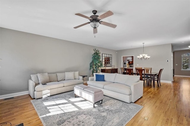 living room with light hardwood / wood-style flooring and ceiling fan with notable chandelier