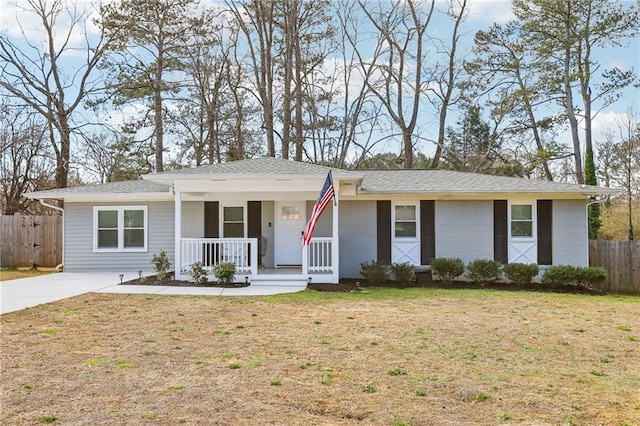 ranch-style home with a porch, fence, a front lawn, and brick siding