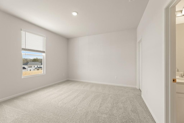 empty room featuring baseboards and light colored carpet