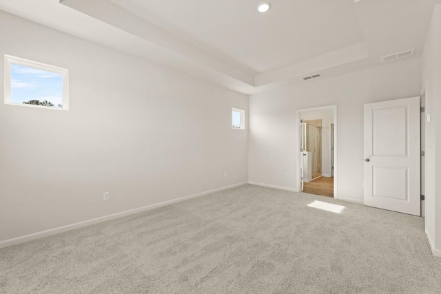 unfurnished bedroom featuring carpet, a raised ceiling, visible vents, and baseboards