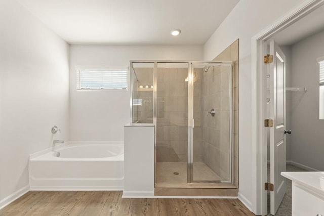 full bathroom featuring vanity, a shower stall, wood finished floors, baseboards, and a bath