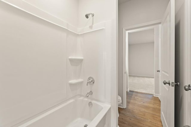 bathroom featuring toilet, wood finished floors, and shower / bathtub combination