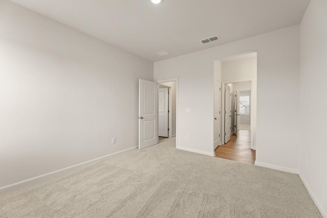 unfurnished bedroom with carpet flooring, visible vents, and baseboards