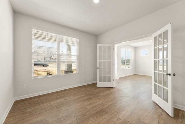 empty room with french doors, wood finished floors, and baseboards