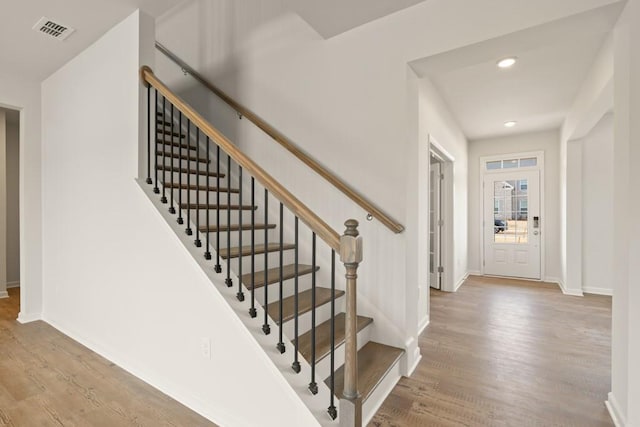 stairway featuring recessed lighting, wood finished floors, visible vents, and baseboards