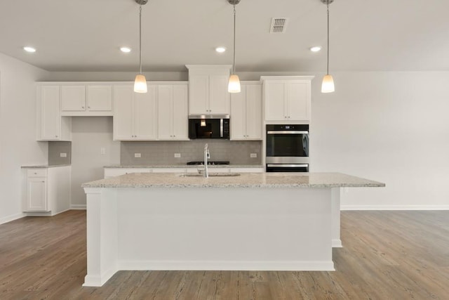 kitchen with a center island with sink, visible vents, appliances with stainless steel finishes, white cabinetry, and a sink