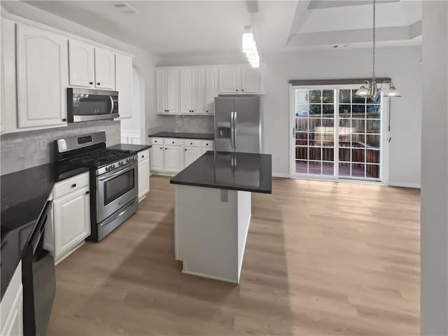 kitchen with stainless steel appliances, dark countertops, tasteful backsplash, light wood-style floors, and white cabinetry