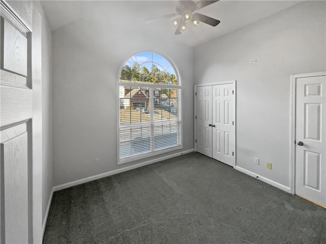 empty room with a ceiling fan, dark carpet, and baseboards