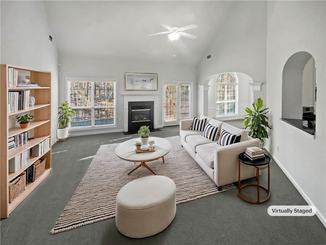 carpeted living area with high vaulted ceiling, baseboards, a fireplace with flush hearth, and a ceiling fan