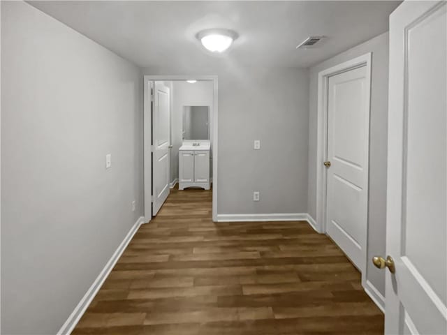 corridor featuring a sink, dark wood finished floors, visible vents, and baseboards