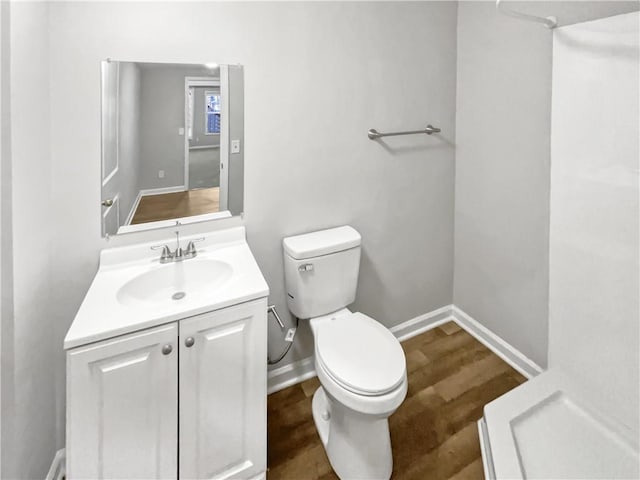 bathroom with baseboards, vanity, toilet, and wood finished floors