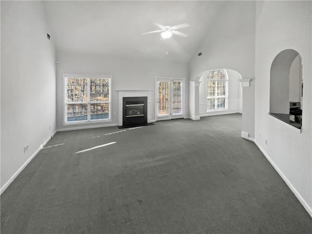 unfurnished living room with high vaulted ceiling, carpet floors, a fireplace with flush hearth, and a healthy amount of sunlight