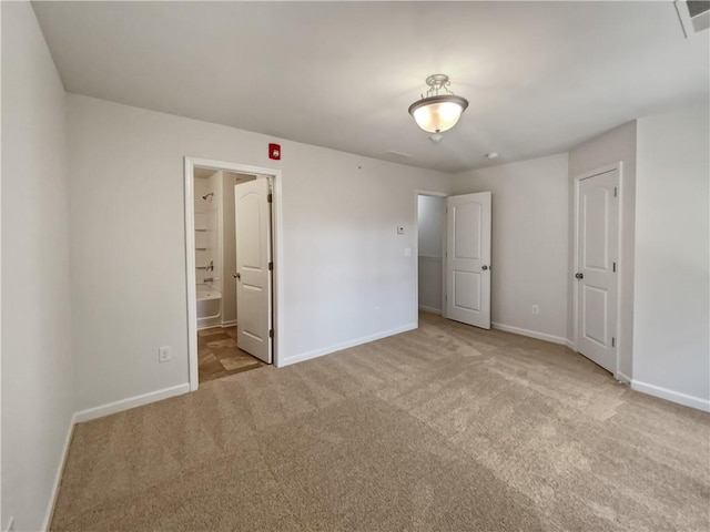 unfurnished bedroom with light colored carpet and connected bathroom