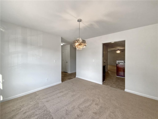 carpeted empty room featuring an inviting chandelier