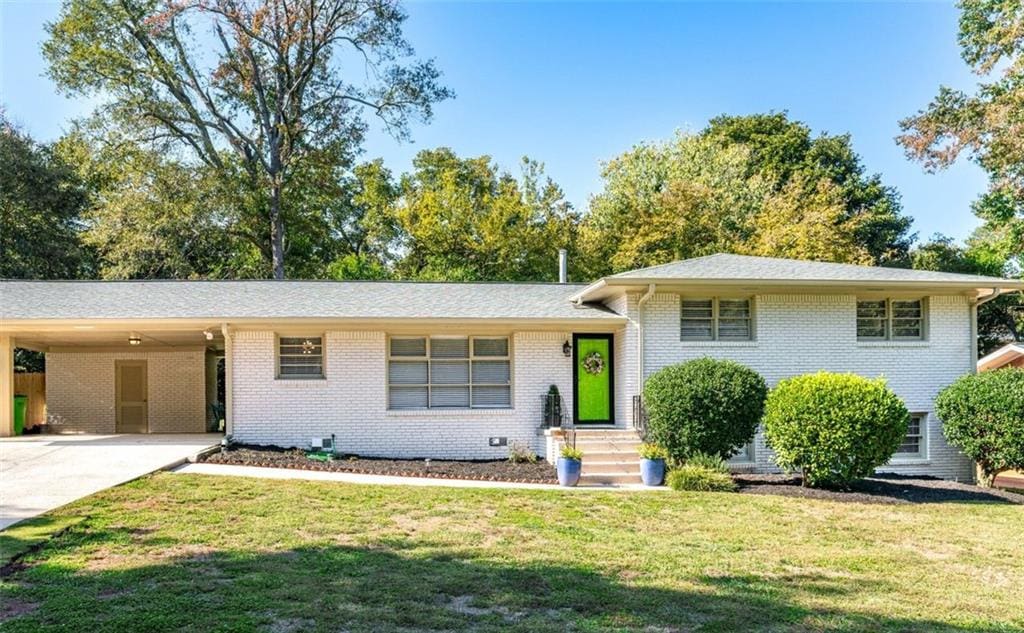 1151 Bromley Rd, Avondale Estates, GA 30002 - split level home featuring a front lawn, concrete driveway, brick siding, and an attached carport