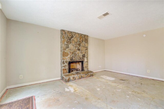 unfurnished living room with a stone fireplace and a textured ceiling