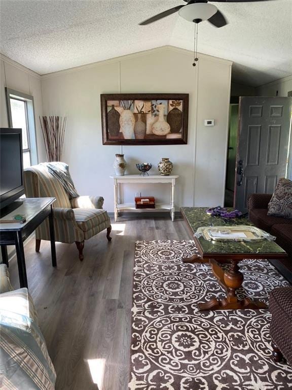 living room with dark wood-type flooring, vaulted ceiling, a textured ceiling, and ceiling fan