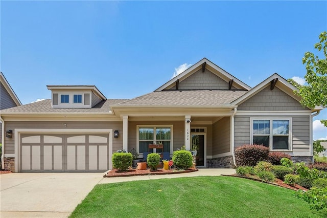 craftsman-style home with driveway, stone siding, roof with shingles, a front yard, and an attached garage