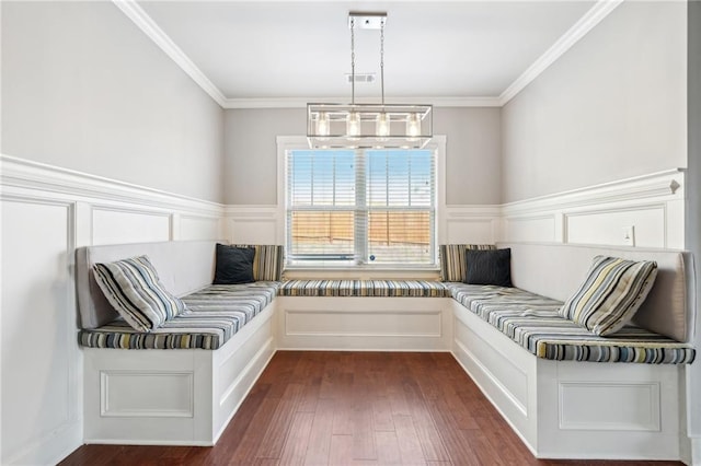 unfurnished room featuring dark wood-type flooring, wainscoting, crown molding, and a decorative wall