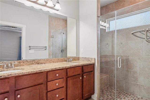 full bath featuring double vanity, a stall shower, and a sink